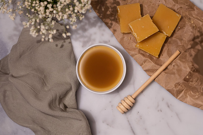 Beeswax candle glowing warmly on a table, creating a tranquil and relaxing atmosphere, perfect for self-care routines.