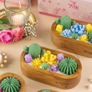 A beautifully crafted wooden container filled with colorful, cactus-shaped and succulent-shaped scented candles, featuring vibrant green, yellow, blue, and purple tones. The candles resemble a miniature garden of cacti and succulents, offering an aesthetic and fragrant touch to any space.