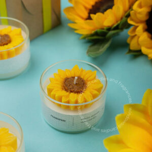 Handcrafted sunflower beeswax candle by Windowsill displayed on a blue background with sunflower decorations.